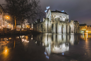 Fototapeta na wymiar Night Gravensteen view - historical medieval castle on water in Ghent, Flanders, Belgium. Castle of Counts stronghold reflected on canal in Gent city by evening illumination.