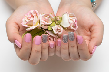 pink manicure with silver sequins on square nails with roses in palms on white background

