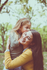 Fototapeta premium Mother and daughter in city park. Front view.