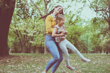 Mother playing in nature with daughter. Spinning  around little girl.