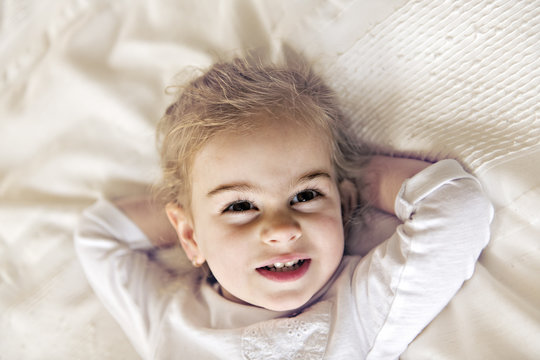 young daughter two years old relaxing in bed, positive feelings