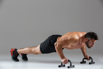 Full length portrait of a muscular strong shirtless male bodybuilder