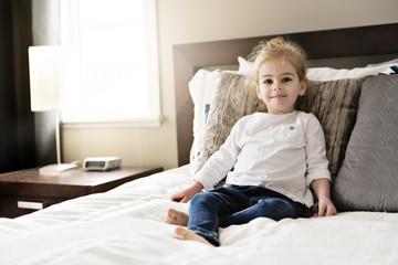 young daughter two years old relaxing in bed, positive feelings