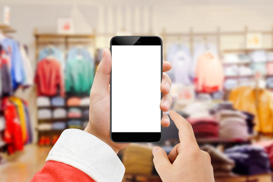 Santa Claus holding smartphone with blank screen, fashion store in background. Christmas online shopping concept