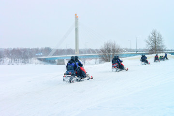 People riding snowmobiles at Candle Bridge Rovaniemi