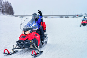 People riding snowmobiles and waving hands Rovaniemi