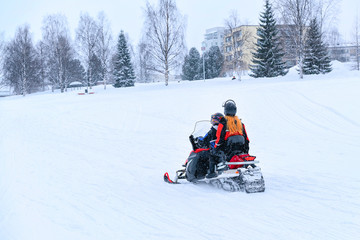 Fototapeta na wymiar People riding snowmobile at frozen snow lake in winter Rovaniemi