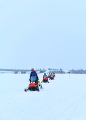 Fototapeta na wymiar Peopla riding snowmobiles on frozen lake at winter Rovaniemi