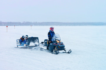 Man riding snowmobile with kids in frozen lake winter Rovaniemi