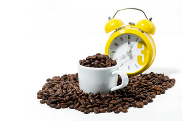 cup with coffee beans and yellow alarm clock on white background