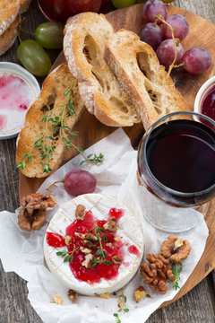 delicious appetizers for wine - camembert, berry jam, toast and fruit, close-up, top view
