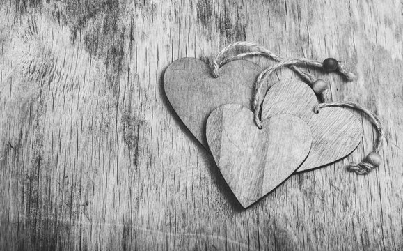 Stack of wooden hearts on an old board. Wooded valentines on a wooden background. Monochrome