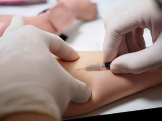 A physician wearing latex gloves performs an intradermal injection at a pediatric patient's forearm. Healthcare and vaccination concept.