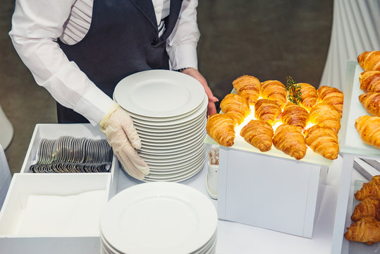 The waiter is servering catering buffet table with food and snacks for guests of the event. Dining Food Celebration Party Concept. Service at business meeting, weddings. Selective focus