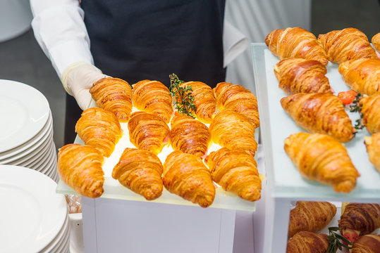 The waiter is servering catering buffet table with food and snacks for guests of the event. Dining Food Celebration Party Concept. Service at business meeting, weddings. Selective focus