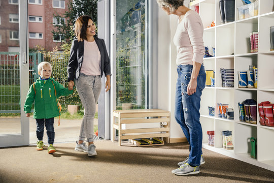 Smiling mother bringing boy to kindergarten