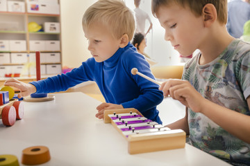Two boys playing with musical instruments and toys in kindergarten