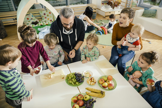 Group of children and teachers preparing fruit in kindergarten - Powered by Adobe
