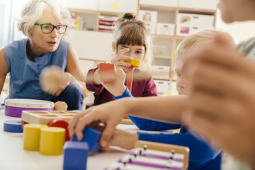 Children and teacher playing with musical instruments and toys in kindergarten