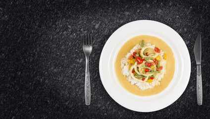Squid rings in chilli curry sauce with green beans, tomatoes, peppers. Served with rice. Thai food. On granite kitchen counter top.