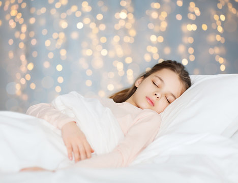 girl sleeping in bed over holidays lights