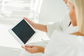 Fototapeta na wymiar cropped shot of young women using digital tablet at spa center