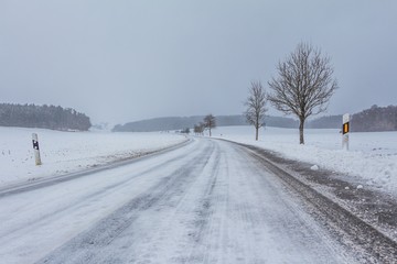 Leere glatte gefrorene Winter Straße mit Eis Schnee nach Sturm. Die Fahrbahn ist weiß glatt...
