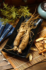 .ginseng in black plate on wooden table