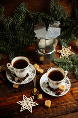 Two cups of espresso with pieces of cane sugar and Italian coffee maker on wooden table.