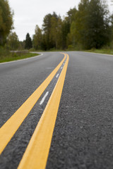 Curvy asphalt road on autumn day in Finland. Yellow lines and clean road. Highway to drive.