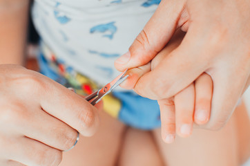 closeup of a mother with a pair of scissors to trim baby nails