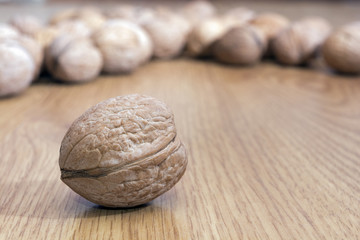 Many walnuts in shell on the table. One walnut close-up against the background of other nuts. Healthy food. Place for text.
