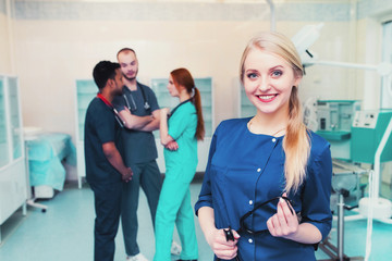 young blond surgeon smiling at the camera with a team of mixed race medical students at the university