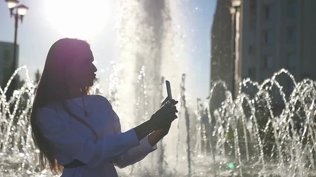 A beautiful girl, makes selfie at the fountain, makes a kiss on the camera. HD, 1920x1080. slow motion.