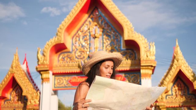 Young Mixed Race Tourist Woman Reading Map and Exploring Thai Buddhist Temple. Phuket, Thailand. 4K, Slowmotion.