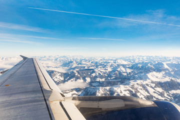 Fototapeta na wymiar Airplane view of mountains with snow and wing
