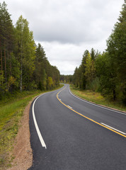 Brand new asphalt road in autumn day. Yellow lines.