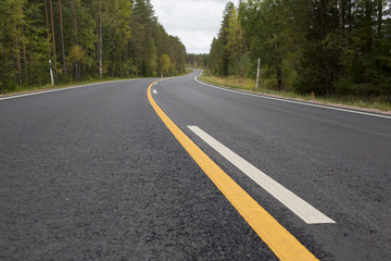 Fototapeta na wymiar Brand new asphalt road in autumn day. Yellow lines.