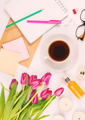 Beautiful flat lay with flowers, cup of tea, glasses, candles and other accessories, concept of a woman's workplace, white background. Toned image