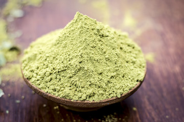 Raw organic powder of henna,Lawsonia inermis in a clay bowl on wooden surface.
