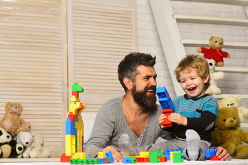 Boy and bearded man play together on wooden wall background