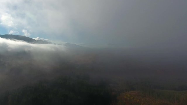 Aerial View. Flying over the high autumn mountains in beautiful clouds . Aerial camera shot. Air clouds
