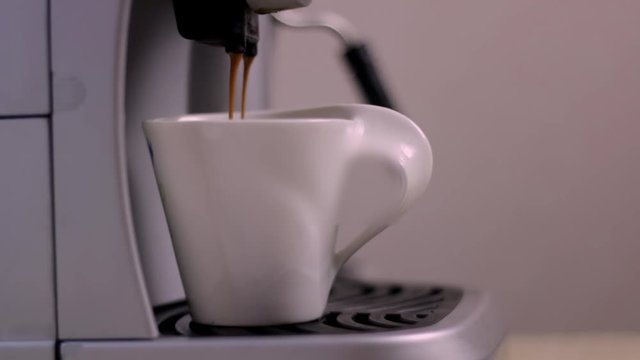 A cup of coffee is on the espresso machine