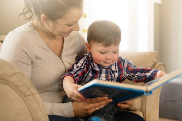 Mother reading book with her child on sofa