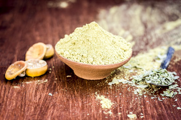 Raw powder of Henna,Lawsonia inermis in a clay bowl with lemons and cloves.
