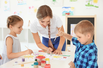 Children with teacher at painting lesson in classroom