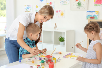 Fototapeta premium Children with teacher at painting lesson in classroom