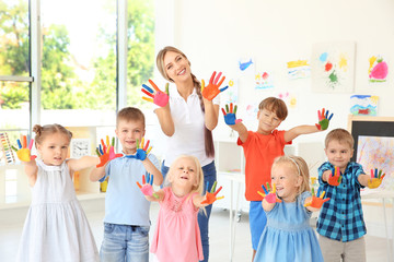 Children and teacher with hands in paint at art lesson - obrazy, fototapety, plakaty