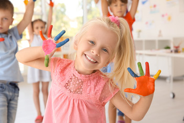 Little girl with hands in paint at art lesson