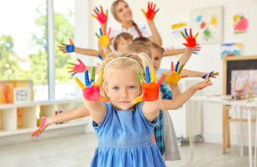 Children and teacher with hands in paint at art lesson